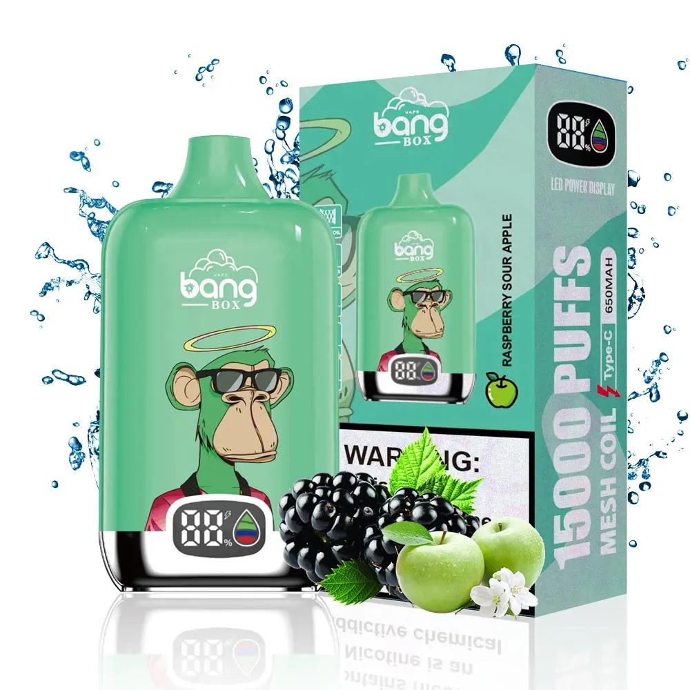 Green Bang Box vape device with a digital display featuring a cartoon monkey wearing sunglasses and a halo, next to its packaging box labeled Raspberry Sour Apple and 15000 puffs, surrounded by water splashes, blackberries, green apples, and apple blossoms.