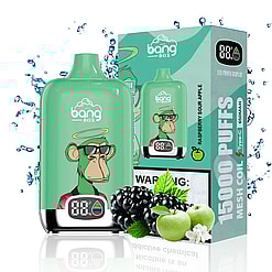 Green Bang Box vape device with a digital display featuring a cartoon monkey wearing sunglasses and a halo, next to its packaging box labeled Raspberry Sour Apple and 15000 puffs, surrounded by water splashes, blackberries, green apples, and apple blossoms.