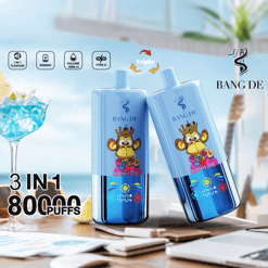 Two blue BANG DE vape devices with a cartoon monkey wearing a crown and pink jacket, displayed on a table with a beach background, alongside a blue cocktail glass and text highlighting 3 in 1 flavor, 650mAh battery, 20ml volume, Type-C charging, and 80,000 puffs.