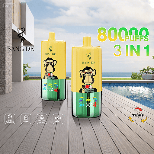 Two yellow and green disposable vape devices with cartoon monkey faces, labeled "BANG DE" and "80000 PUFFS 3 IN 1", placed on a wooden deck near a pool with ocean and sky background.