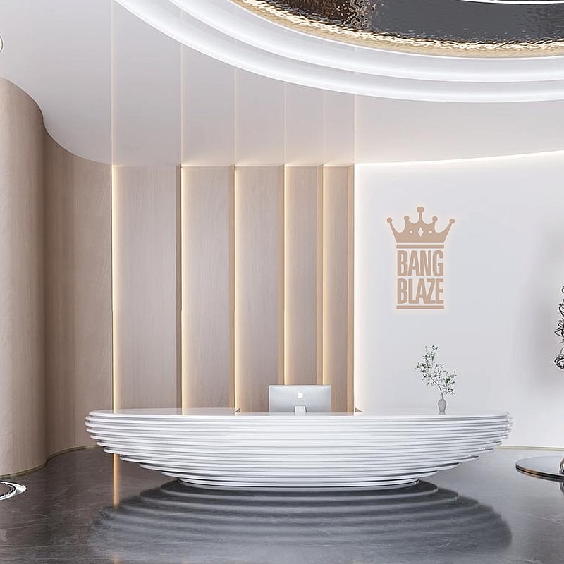 Modern reception area with a white, ribbed oval desk, beige vertical paneling on the wall with integrated warm lighting, a computer monitor on the desk, a small plant on the right side, and the logo 'BANG BLAZE' with a crown displayed on the white wall in a beige tone.
